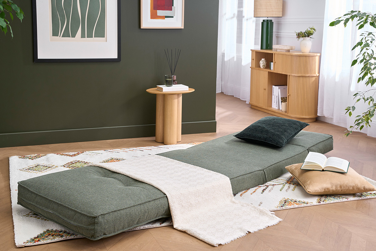 SALLY Schlafsessel in Khakigr�n, ausgeklappt, mit Kissen und Plaid auf Teppich.