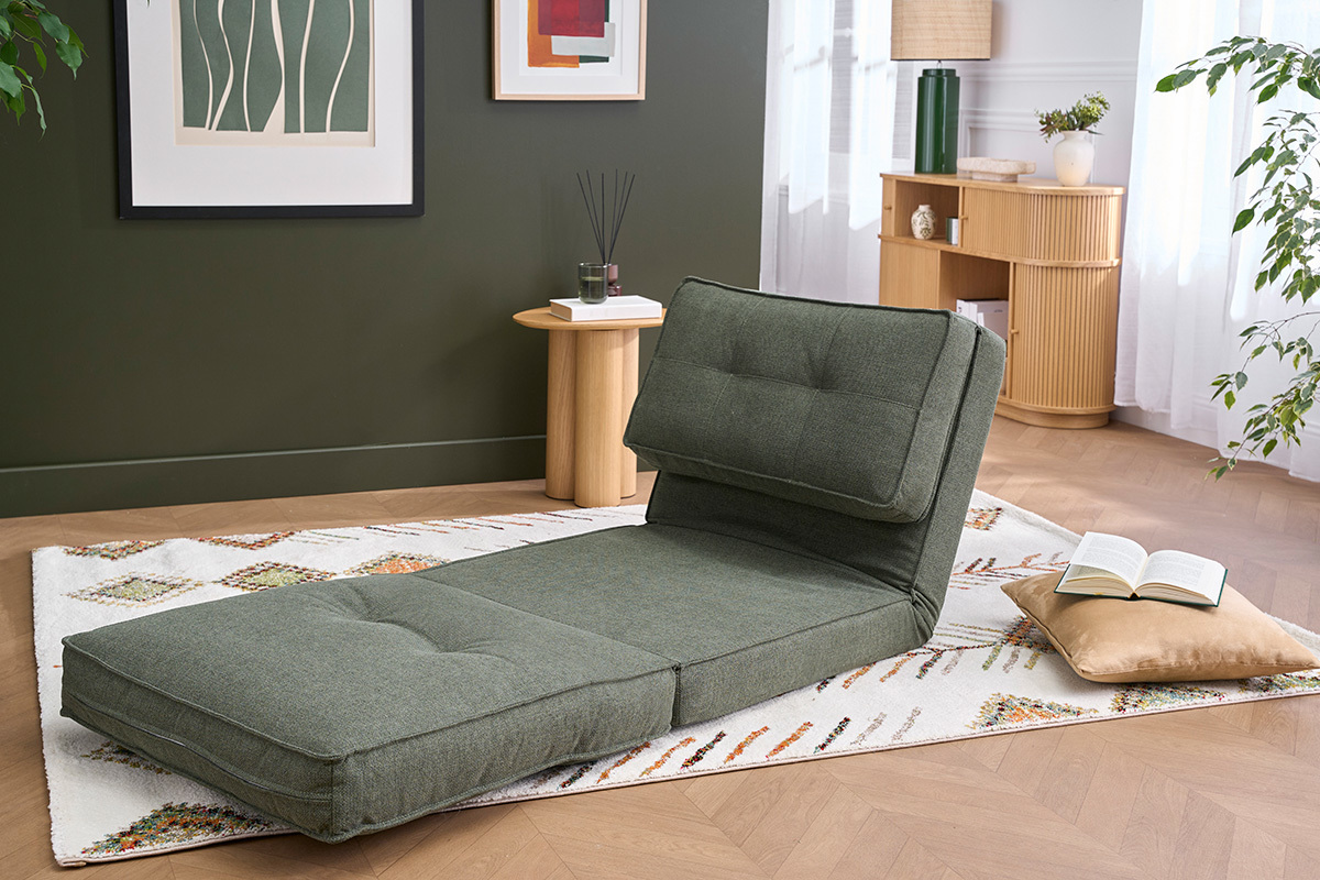 Klappbarer Sessel in Khakigr�nem Stoff, Seitenansicht, auf einem Teppich in einem hellen Wohnzimmer.