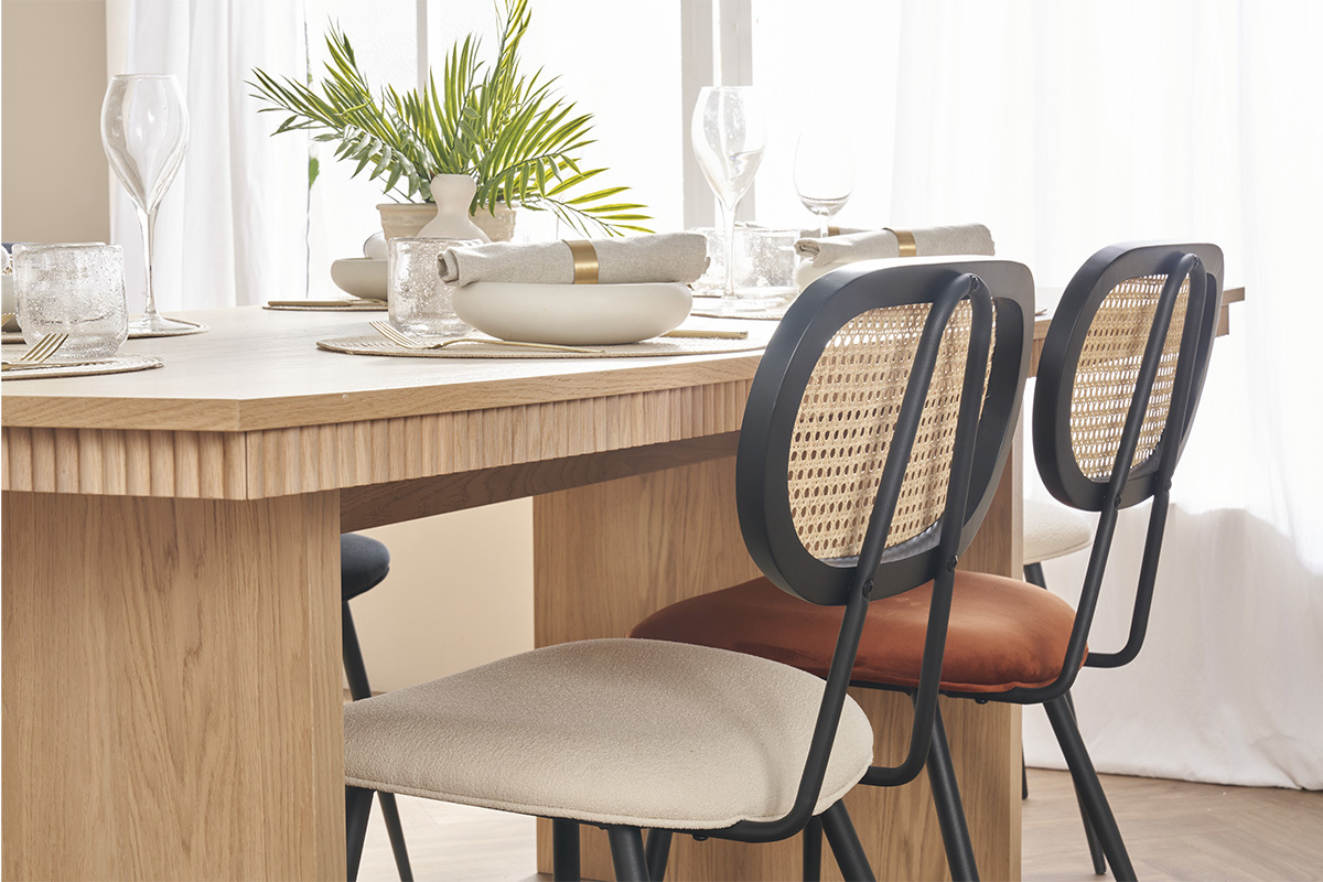 St�hle aus verbranntem Samt und Rattan, um einen hellen Holztisch.