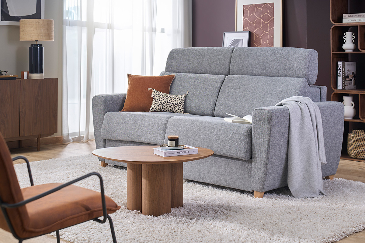 3-Sitzer-Schlafsofa GOYA aus grauem Stoff mit verstellbaren Kopfst�tzen, in 3/4-Ansicht in einem modernen Wohnzimmer.