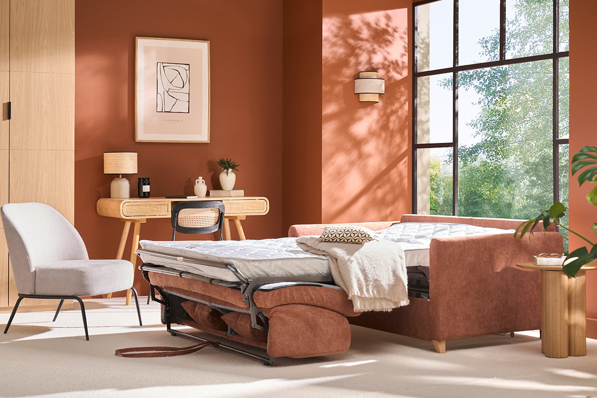 Schlafsofa aus verbranntem-orange Stoff, ausgeklappte Matratze, in einem Wohnzimmer mit terrakottafarbenen Wnden.