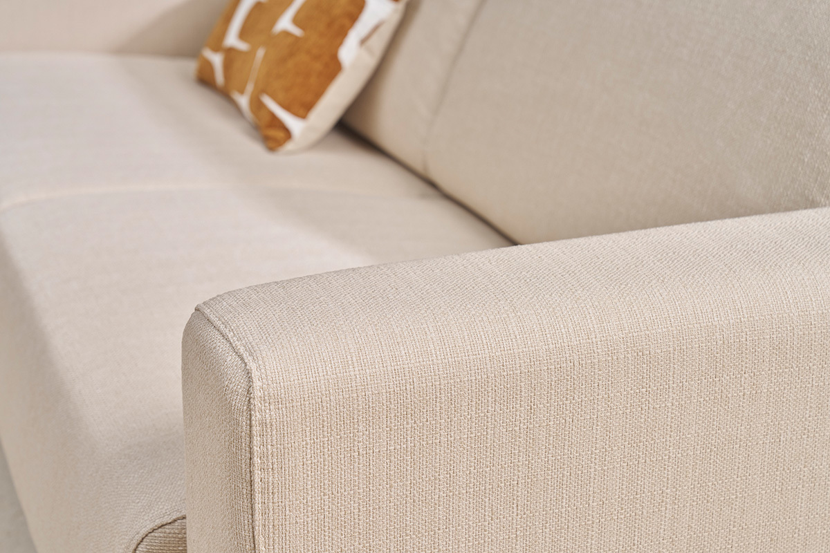 Armlehne eines beigen Stoffsofas mit Zierkissen. Nahaufnahme.
