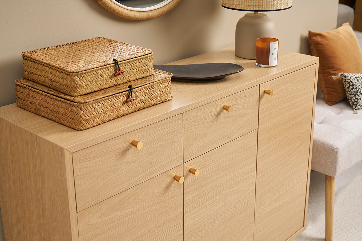 Helles Holzmbel fr den Eingangsbereich mit goldenen Griffen, zwei Weidenkrben und Dekorationen auf der Oberseite.