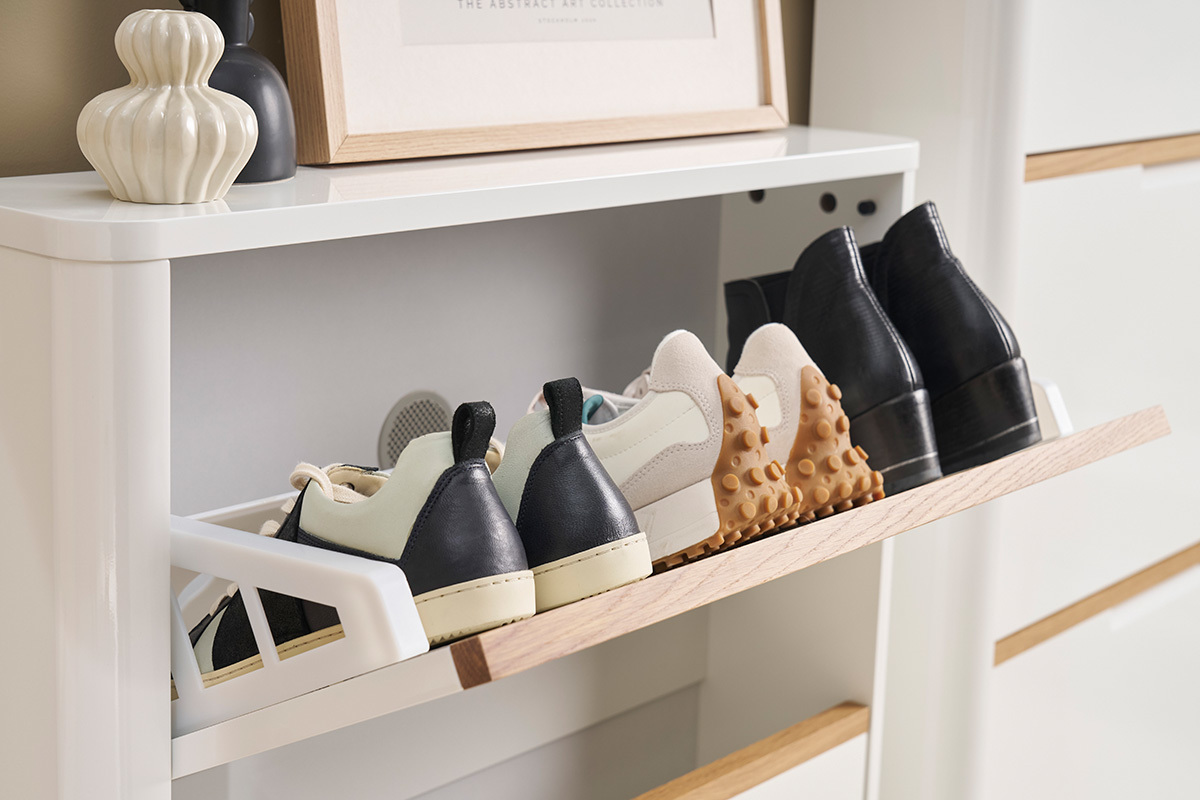 Weier, lackierter Schuhschrank mit geffneter Klappe, Schuhe ordentlich verstaut.