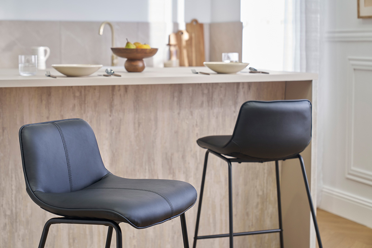 Zwei schwarze Metall-Barhocker vor einer Kchentheke.