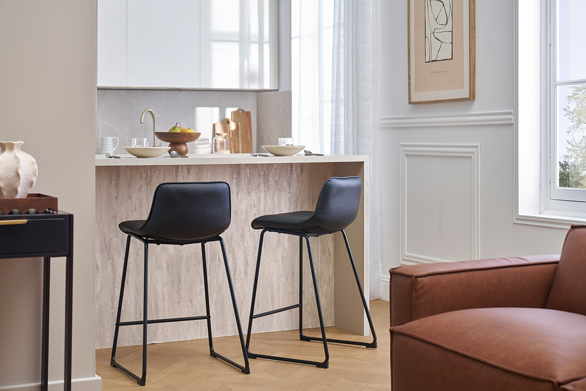 Zwei schwarze und metallene Barhocker H65 cm vor einer Kchentheke.
