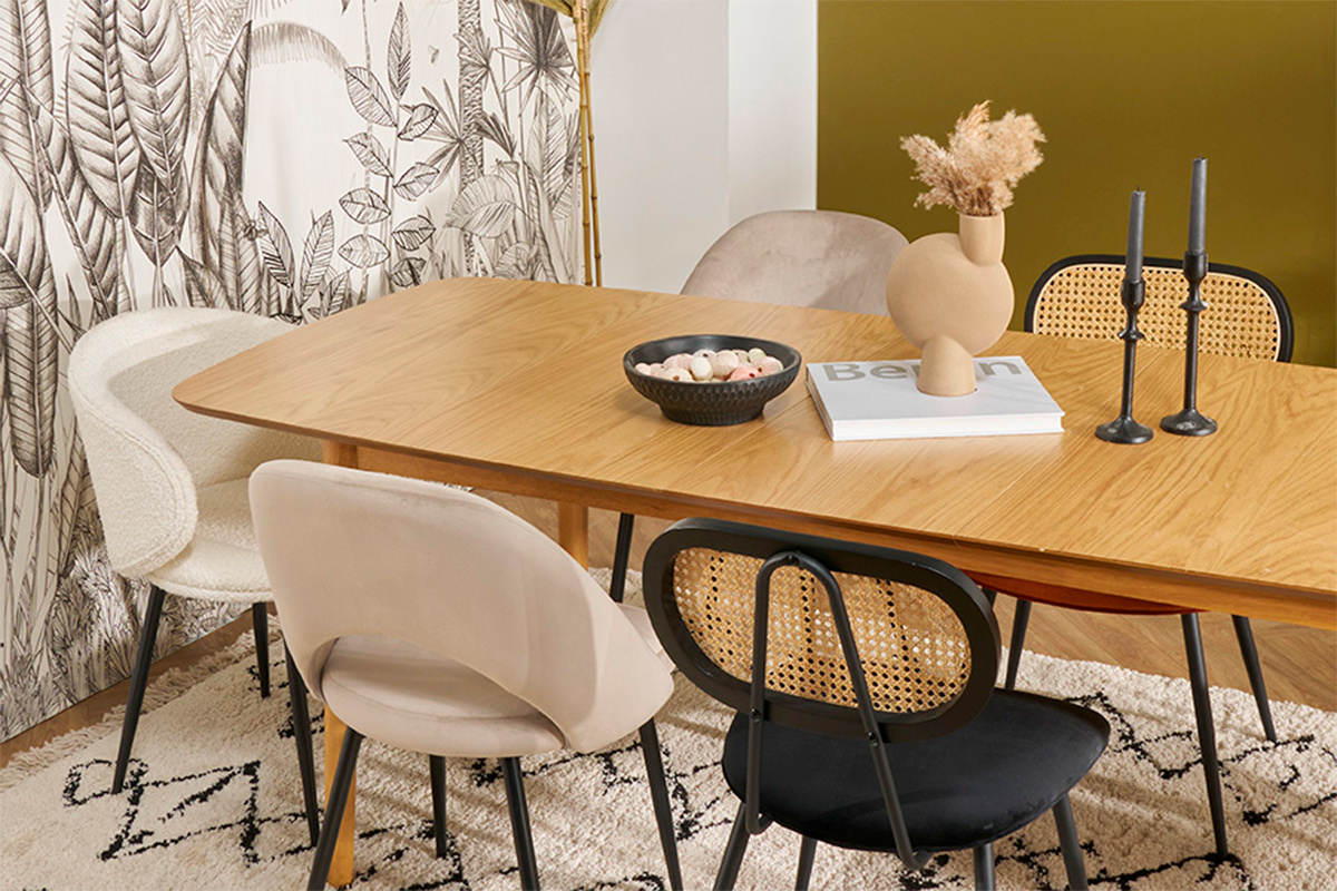 Designersessel aus Samt und Rattan um einen Tisch aus hellem Holz.