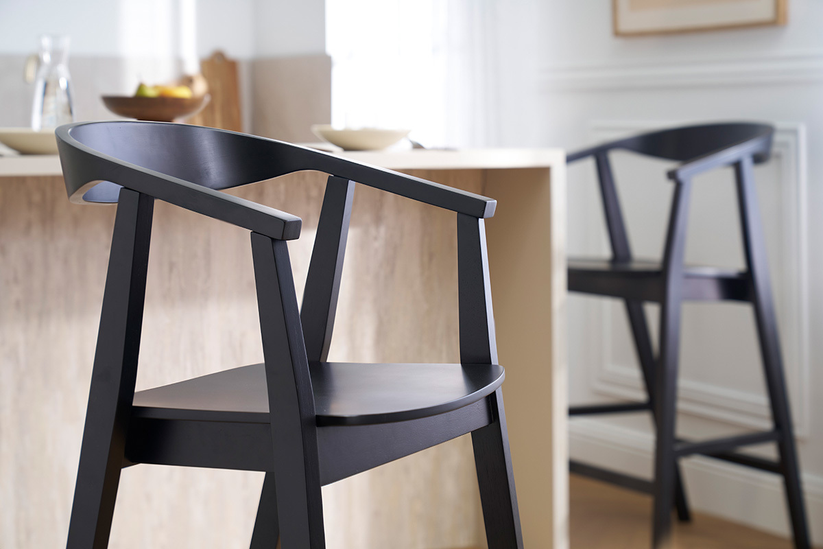 Zwei schwarze BAHIA Barhocker aus Holz neben einer Theke, Nahaufnahme.