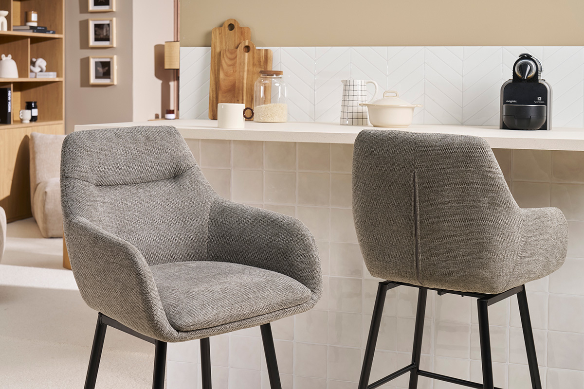 Zwei graue Barhocker aus Stoff, von der Seite und von hinten vor einer Theke gesehen.