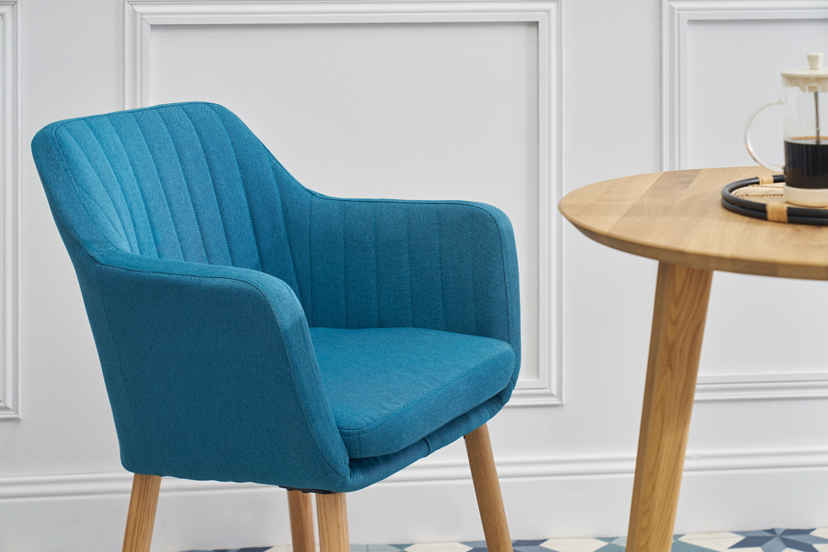 Skandinavischer blauer Stuhl ALEYNA in Stoff, Seitenansicht, mit einem Holztisch.