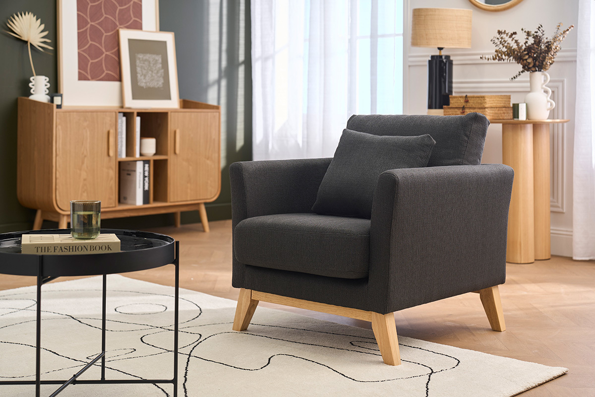 Dunkelgrauer skandinavischer Sessel mit hellem Holz OSLO, Dreiviertelansicht in einem Wohnzimmer.