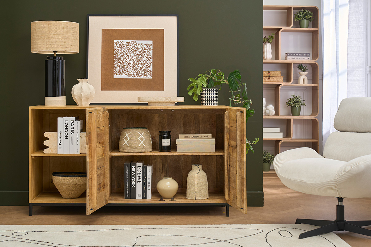 Industriebuffet aus Mangoholz und schwarzem Metall, ge�ffnet mit sichtbaren dekorativen Gegenst�nden, vor gr�nem Hintergrund.