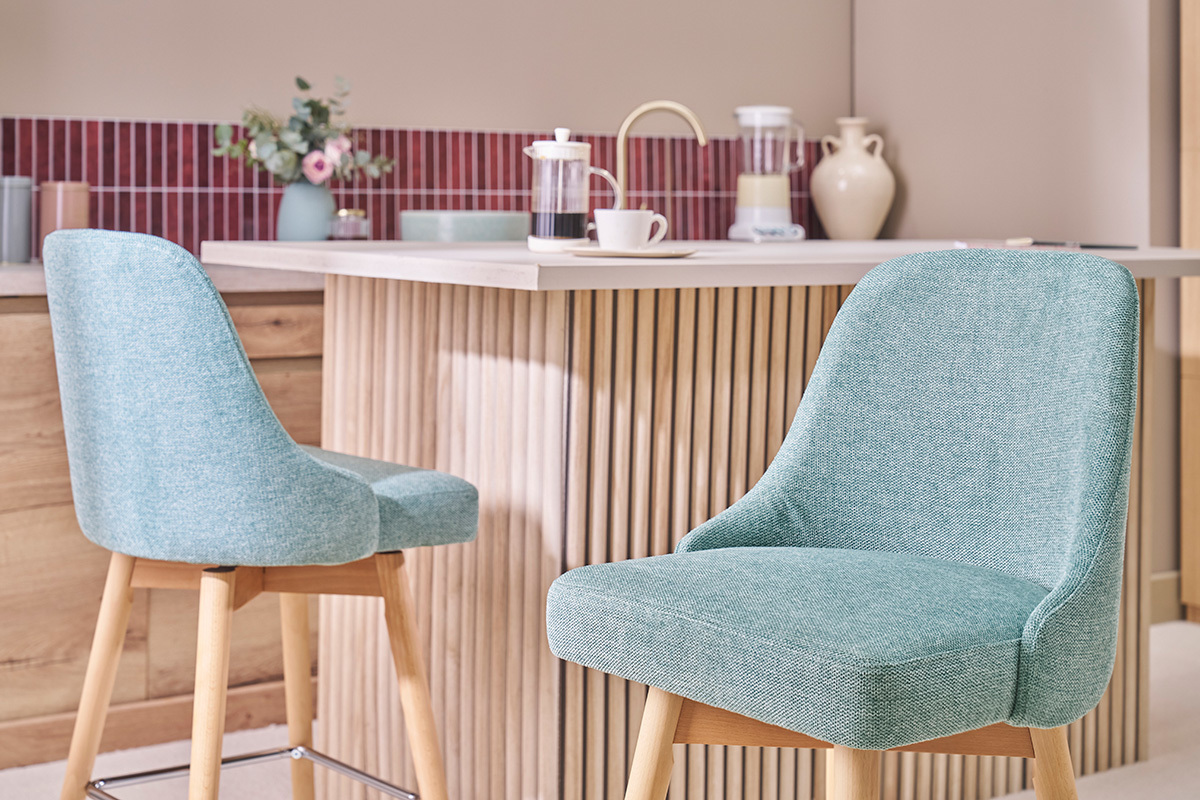 C�ladon gr�ne Barhocker aus Stoff und Holz, vor einer modernen Theke.