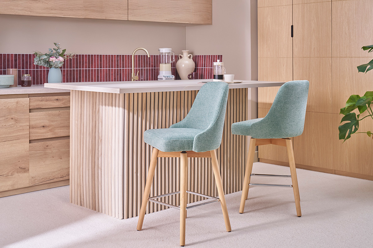 Zwei gr�ne und h�lzerne Barhocker vor einer K�chentheke.