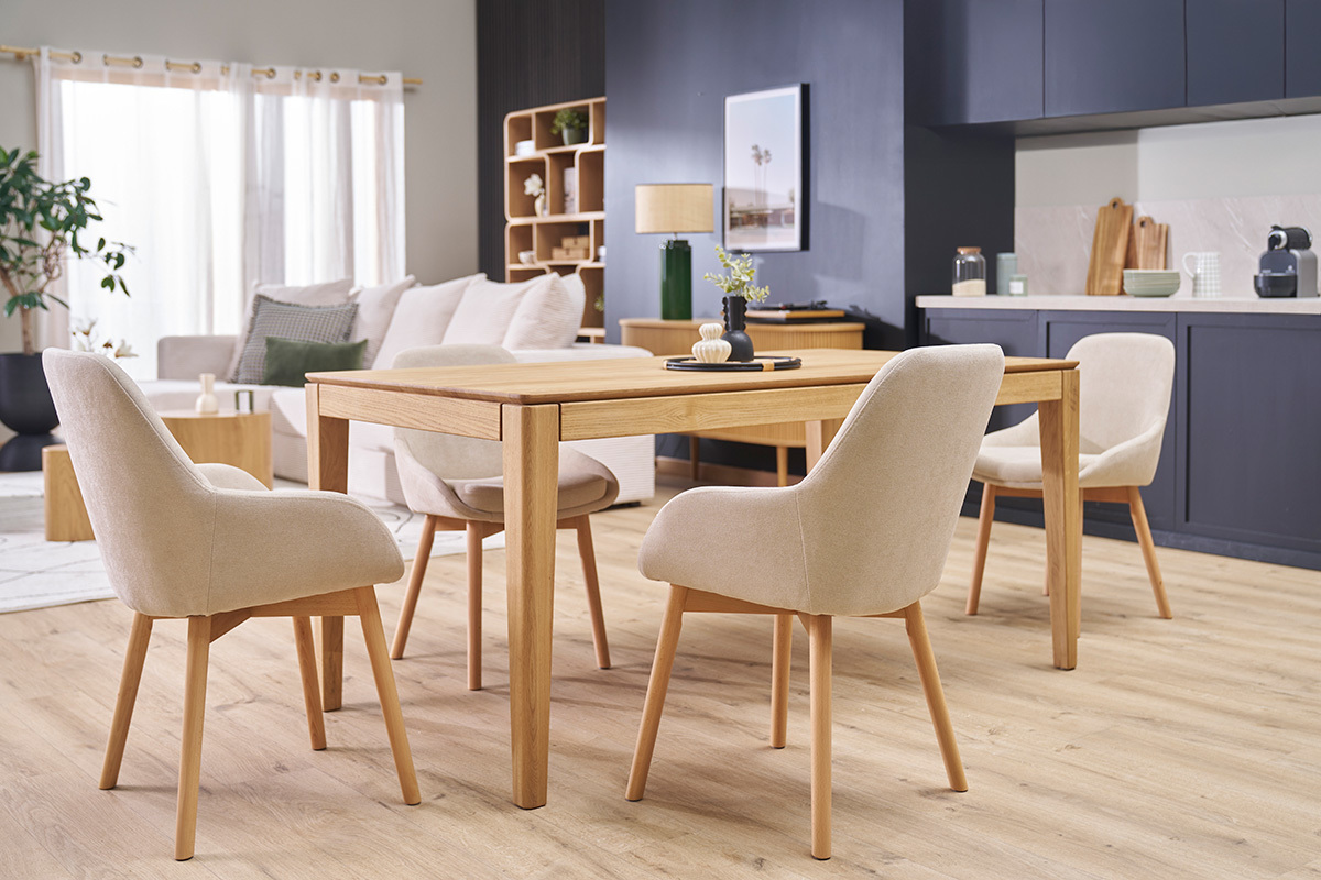 Skandinavische Sessel aus beigem Stoff und hellem Holz um einen Holztisch.