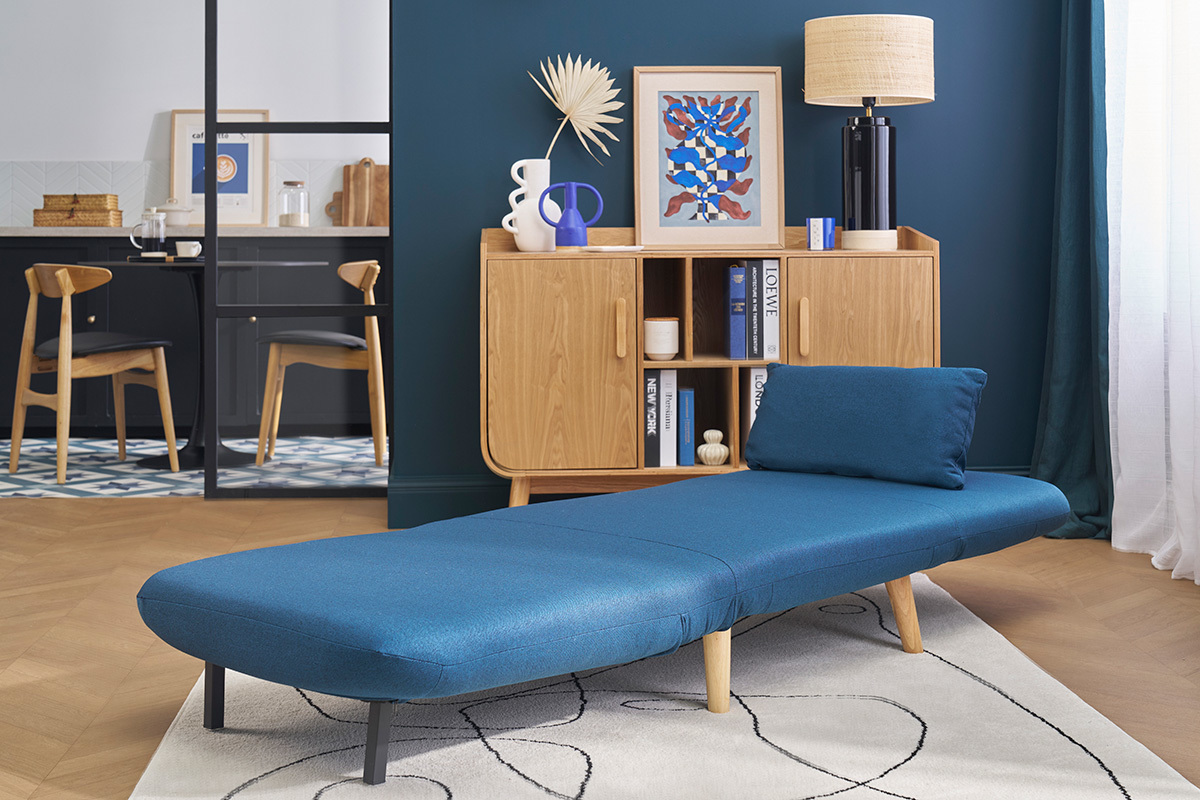 Dunkelblauer Schlafsessel AMIKO ausgeklappt in einem skandinavischen Wohnzimmer.