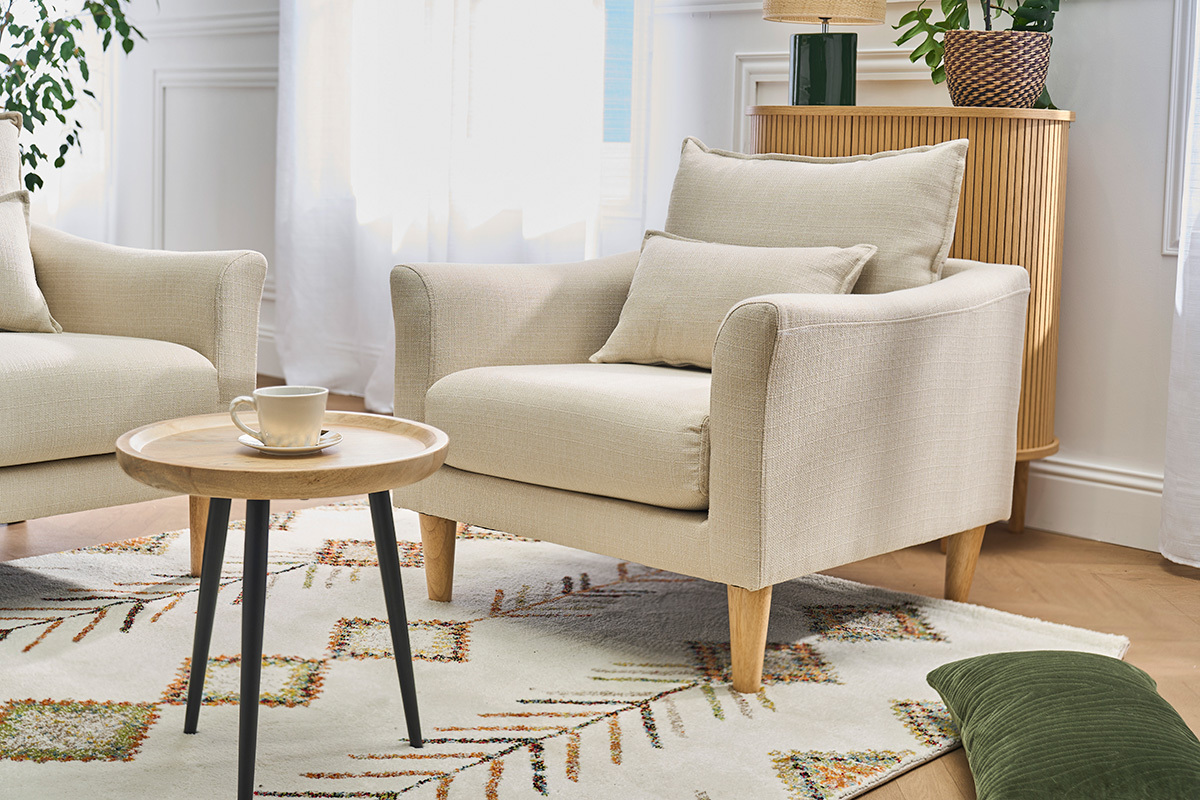 Skandinavischer Sessel in Beige mit Kissen, Couchtisch, Ansicht in Dreiviertelansicht.