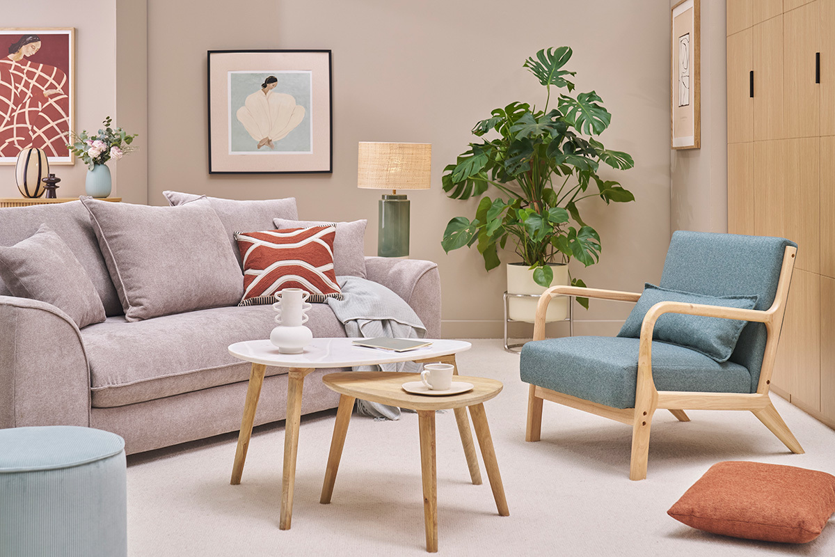 Gr�ngraue DERRY Sessel und helles Holz in einem skandinavischen Wohnzimmer mit Sofa, Tischen und Pflanzen.