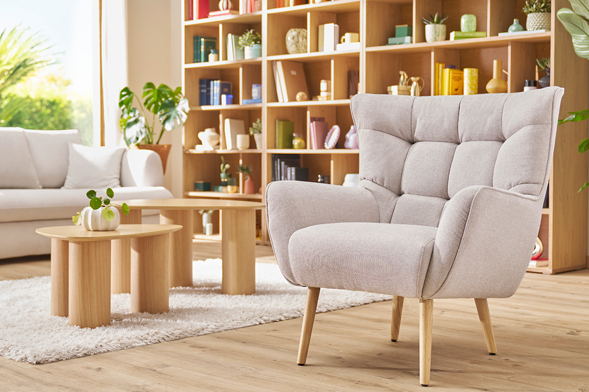 Skandinavischer Sessel AVERY aus beigem Stoff, Holzgestell, in einem hellen Interieur.