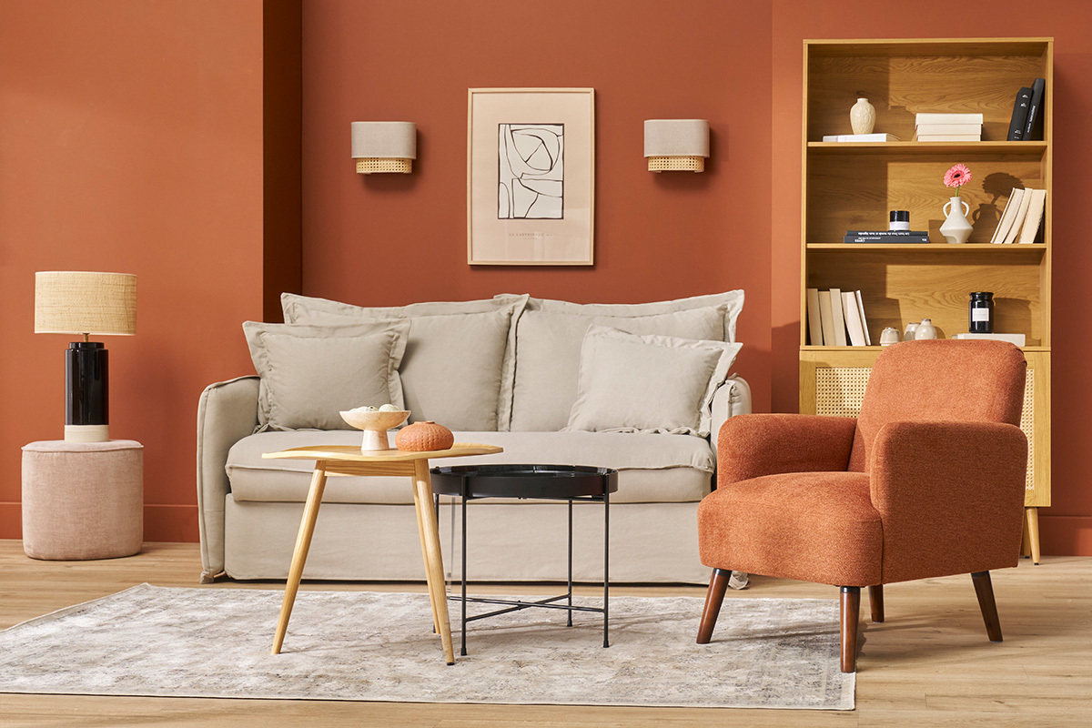 Wohnzimmer mit Sofa, orangefarbenem Stoffsessel, Holzcouchtisch und Regal.