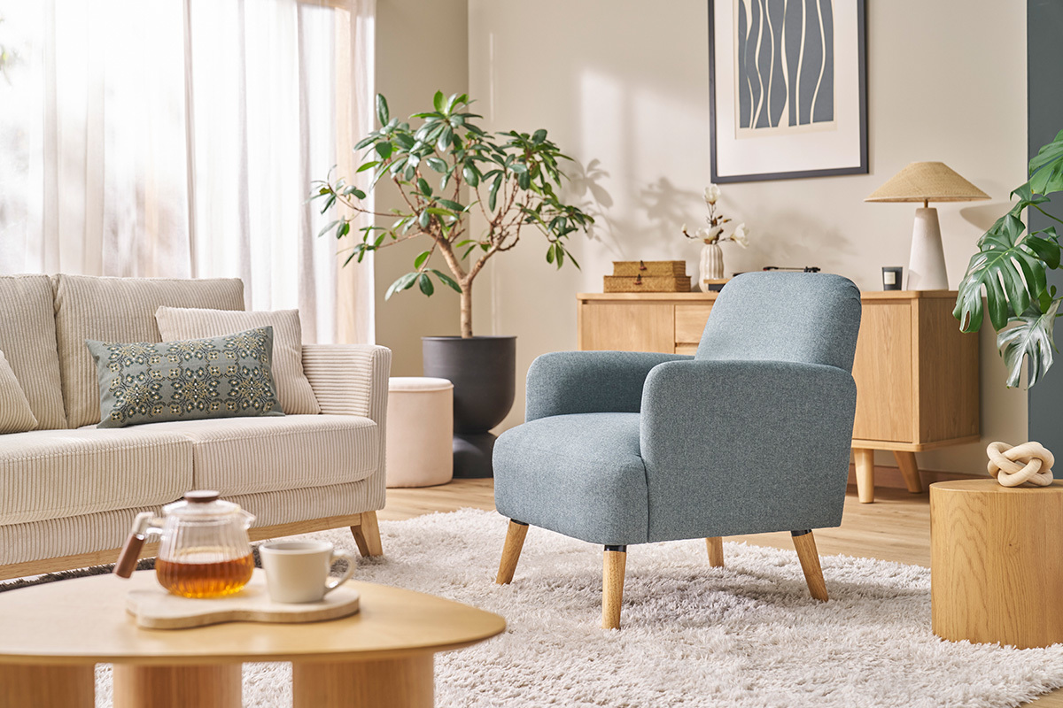 Skandinavischer Stoffsessel mit hellen Holzbeinen, platziert in einem modernen Wohnzimmer.