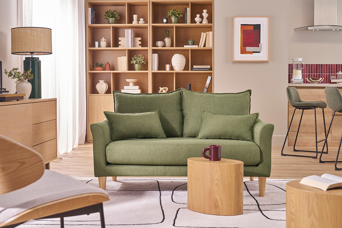 Zweiersofa in khakigr�nem Stoff mit Holzf��en, befindet sich in einem hellen Wohnzimmer.