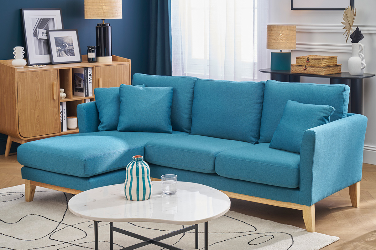 Ecksofa links in Taubenblau mit hellem Holz, in einem Wohnzimmer mit Couchtisch und Holzbuffet.