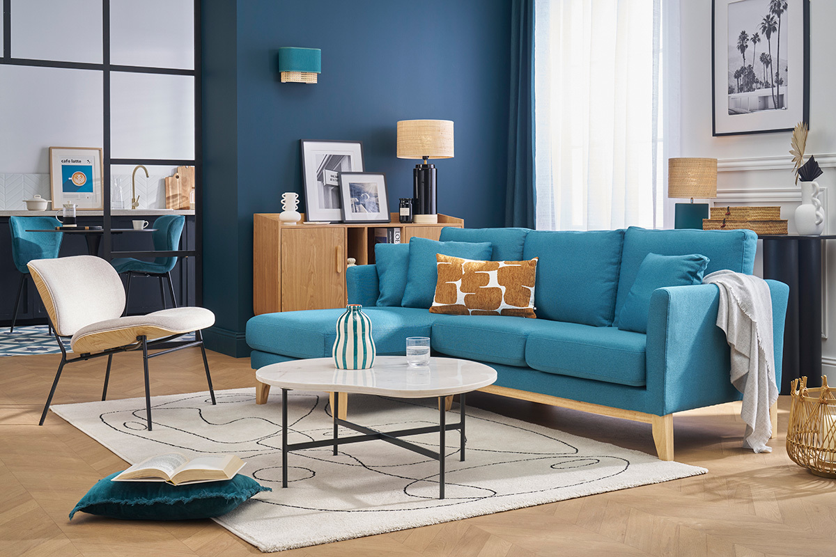 Wohnzimmer mit OSLO Ecksofa in Entenblau, wei�em Couchtisch und beigem Sessel.