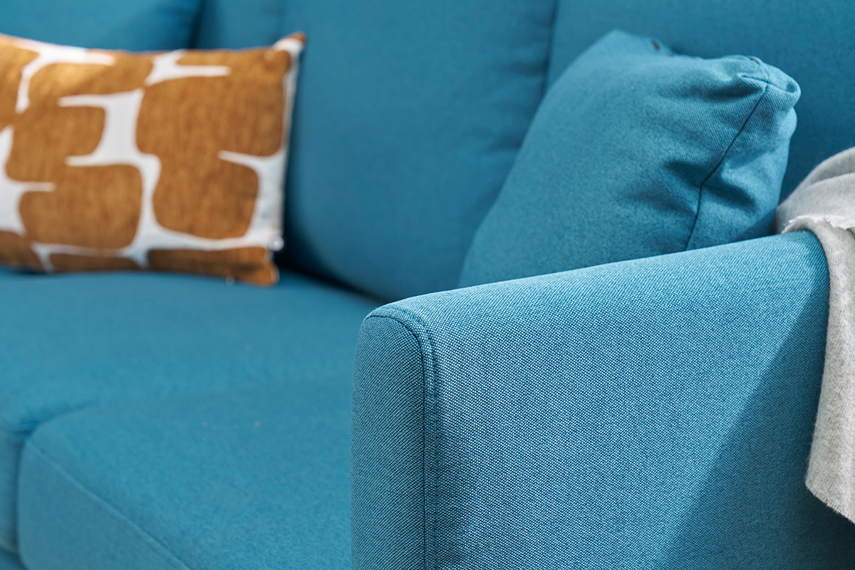 Nahaufnahme einer petrolblauen Eckcouch mit Kissen.