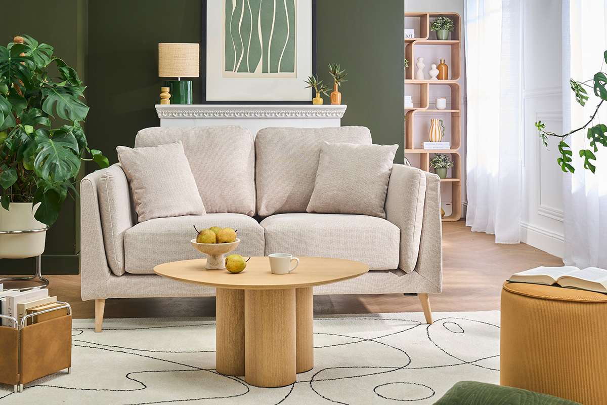 Skandinavisches 2-Sitzer-Sofa VOGUE aus beigem Stoff mit Kissen, Frontansicht in einem stilvollen Wohnzimmer.