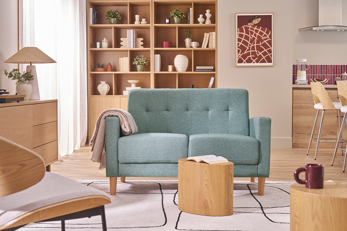 Skandinavisches 2-Sitzer-Sofa in Graugr�n mit getufteter R�ckenlehne, in einem Wohnzimmer.