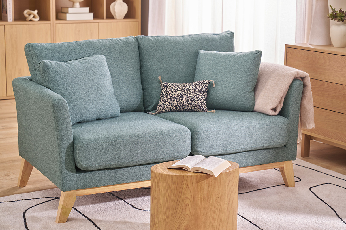 Zweiersofa im skandinavischen Stil in Graugr�n mit Kissen, Couchtisch davor.