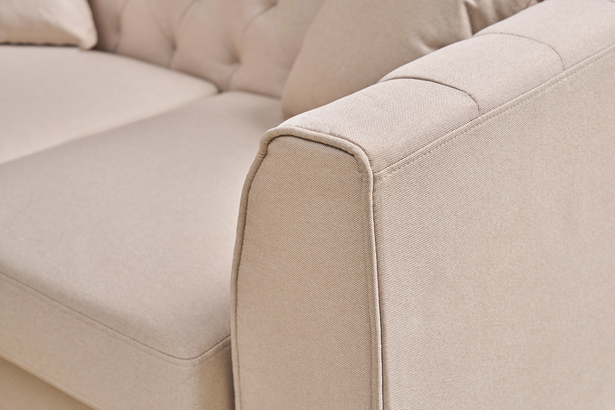 Nahaufnahme der Armlehne des 2-Sitzer Sofas MONTAIGNE in beigem Stoff mit Knopfheftung.