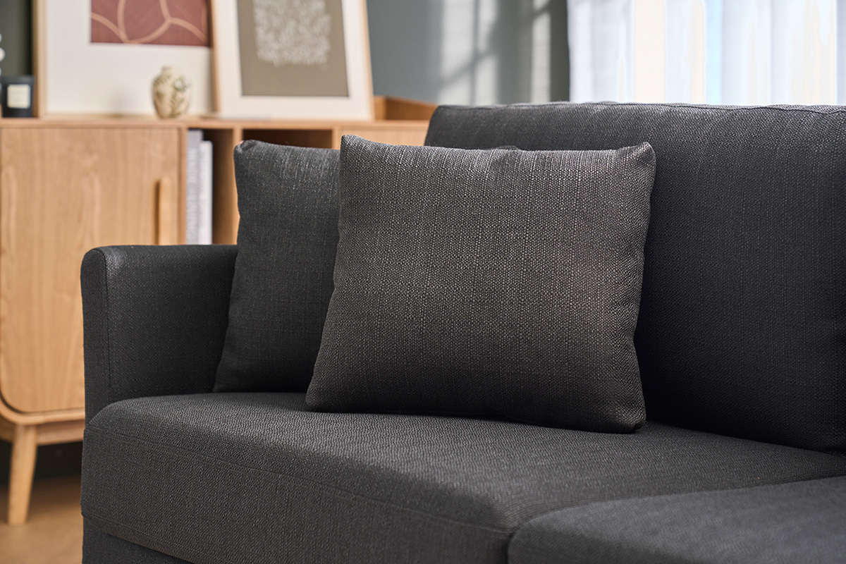 Dunkelgraues skandinavisches Sofa mit Kissen, teilweise Ansicht, helles Holzm�bel im Hintergrund.
