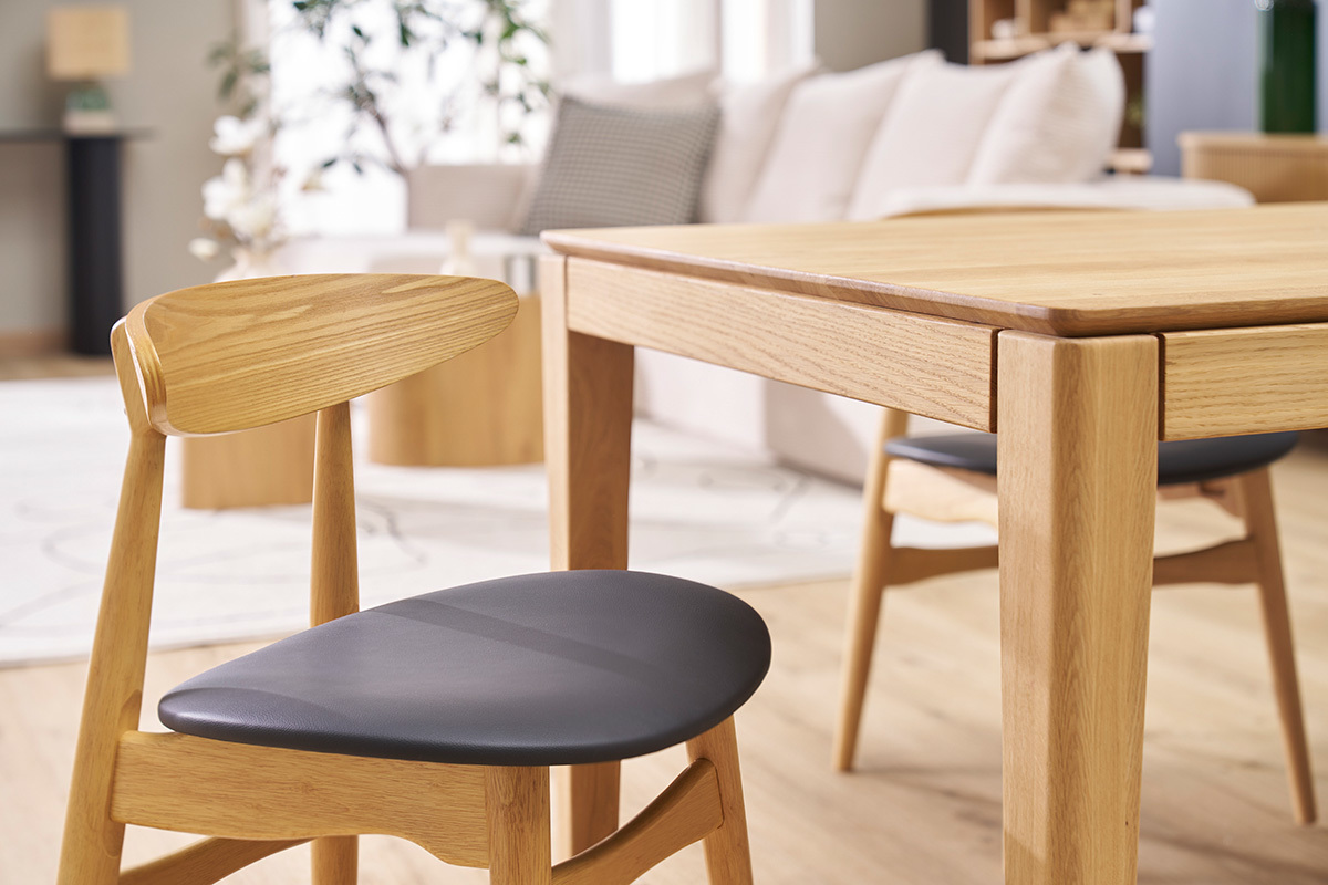 WALFORD Sthle aus hellem Holz und Schwarz um einen Tisch aus hellem Holz, Seitenansicht.