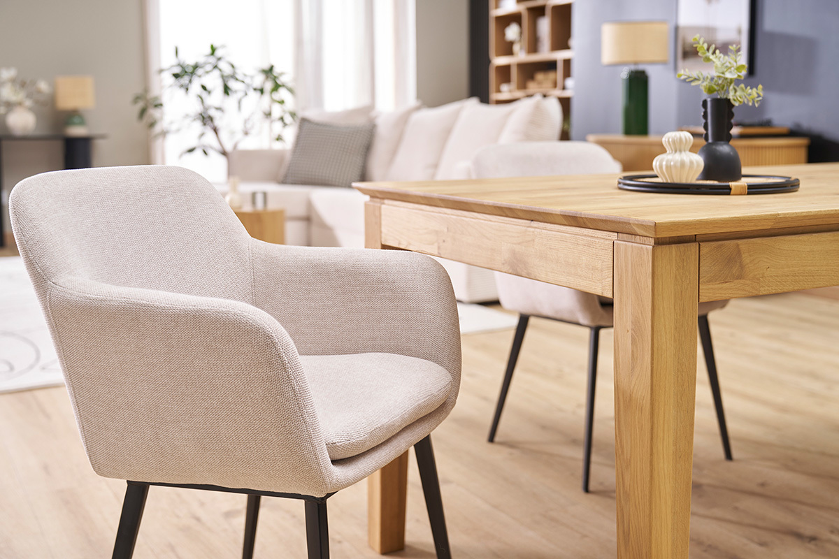 St�hle aus beigefarbenem Samtstoff und schwarzem Metall, um einen Holztisch in einem zeitgen�ssischen Wohnzimmer.