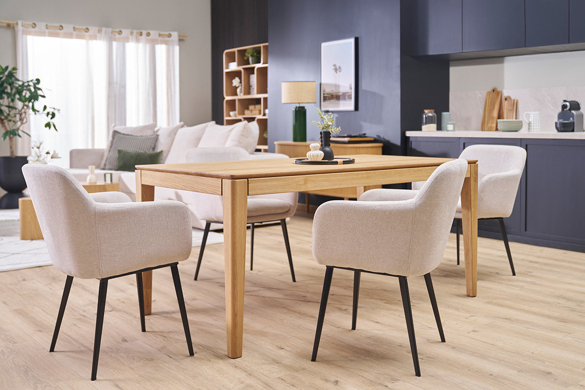 Vier St�hle aus beigefarbenem Stoff und schwarzem Metall um einen Holztisch, Eckansicht in einem Wohnzimmer.