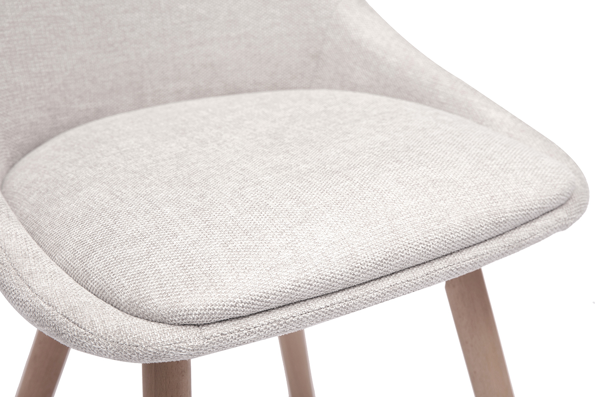 Nahaufnahme des gepolsterten Sitzes eines Stuhls aus beigem Samtstoff und mit hellen Holzbeinen.