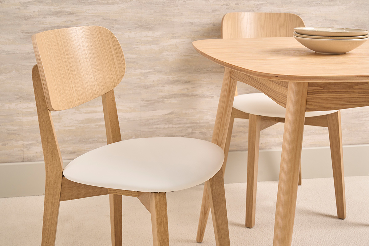 Vintage-St�hle aus hellem Eichenholz mit wei�em Sitz, Nahaufnahme von zwei St�hlen um einen Tisch.