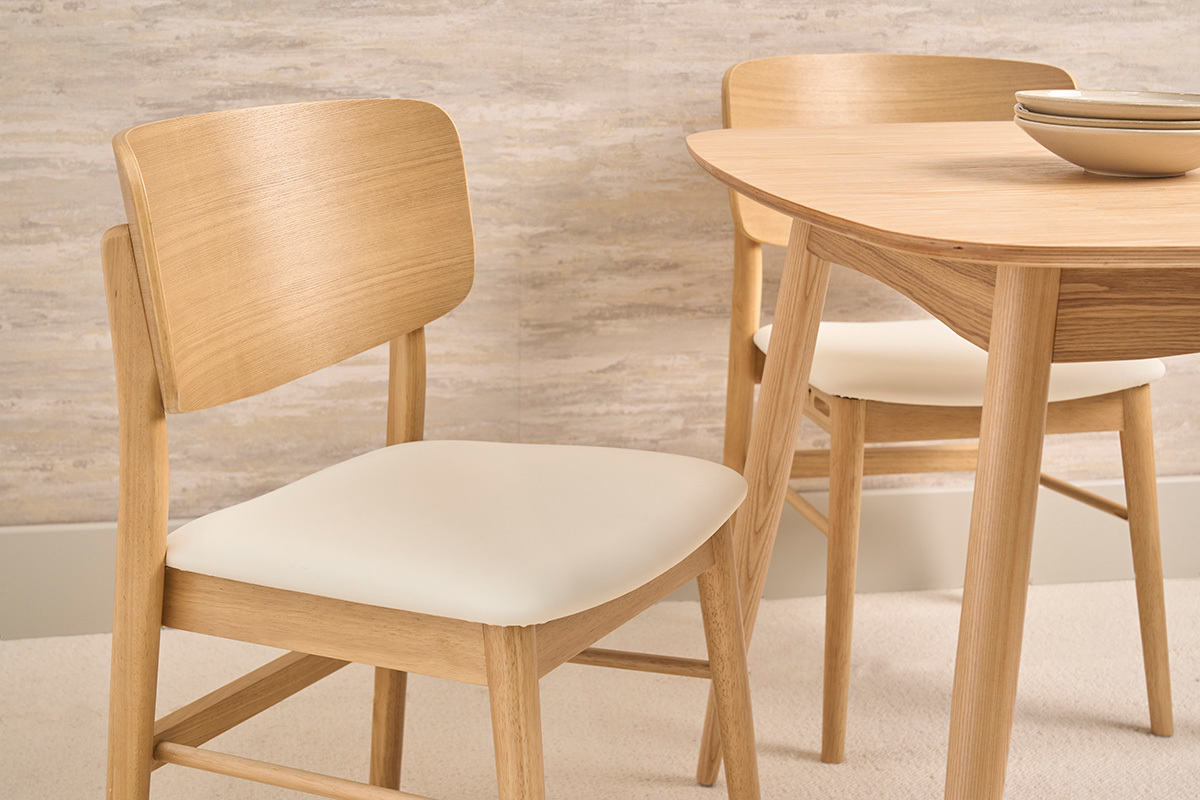Wei�e skandinavische St�hle und helles Holz, Nahaufnahme, mit einem Holztisch im Hintergrund.