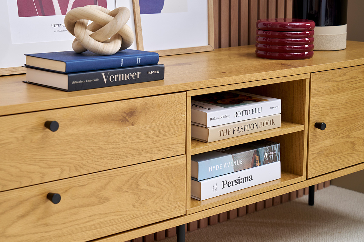 Nahaufnahme eines hellen Holzfernsehmbels mit Bchern und dekorativen Objekten darauf.