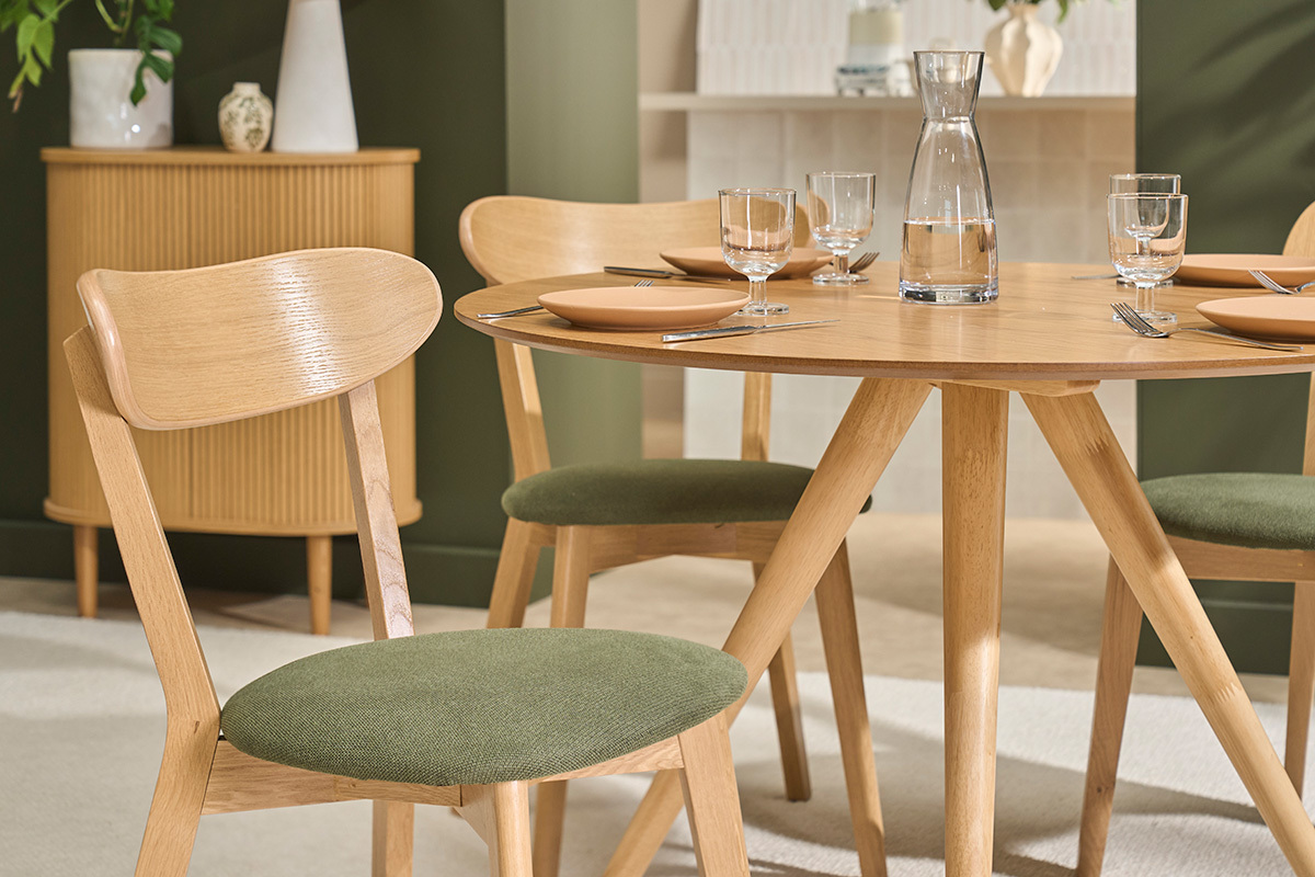 Vintage-DOVE-St�hle aus hellem Holz mit Sitzfl�che aus khakigr�nem Stoff, neben einem runden Tisch gesehen.