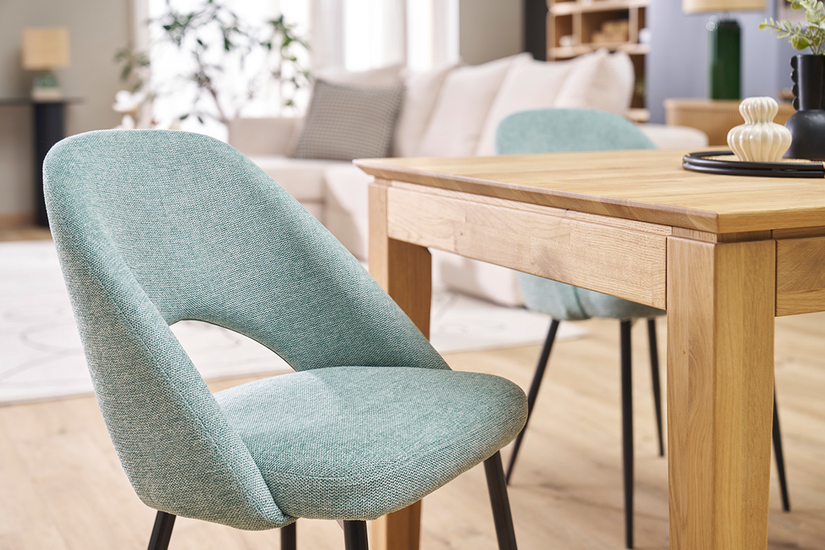 Gr�ne Vintage-St�hle mit schwarzen Beinen, nahe einem Holztisch, in einem modernen Wohnzimmer.