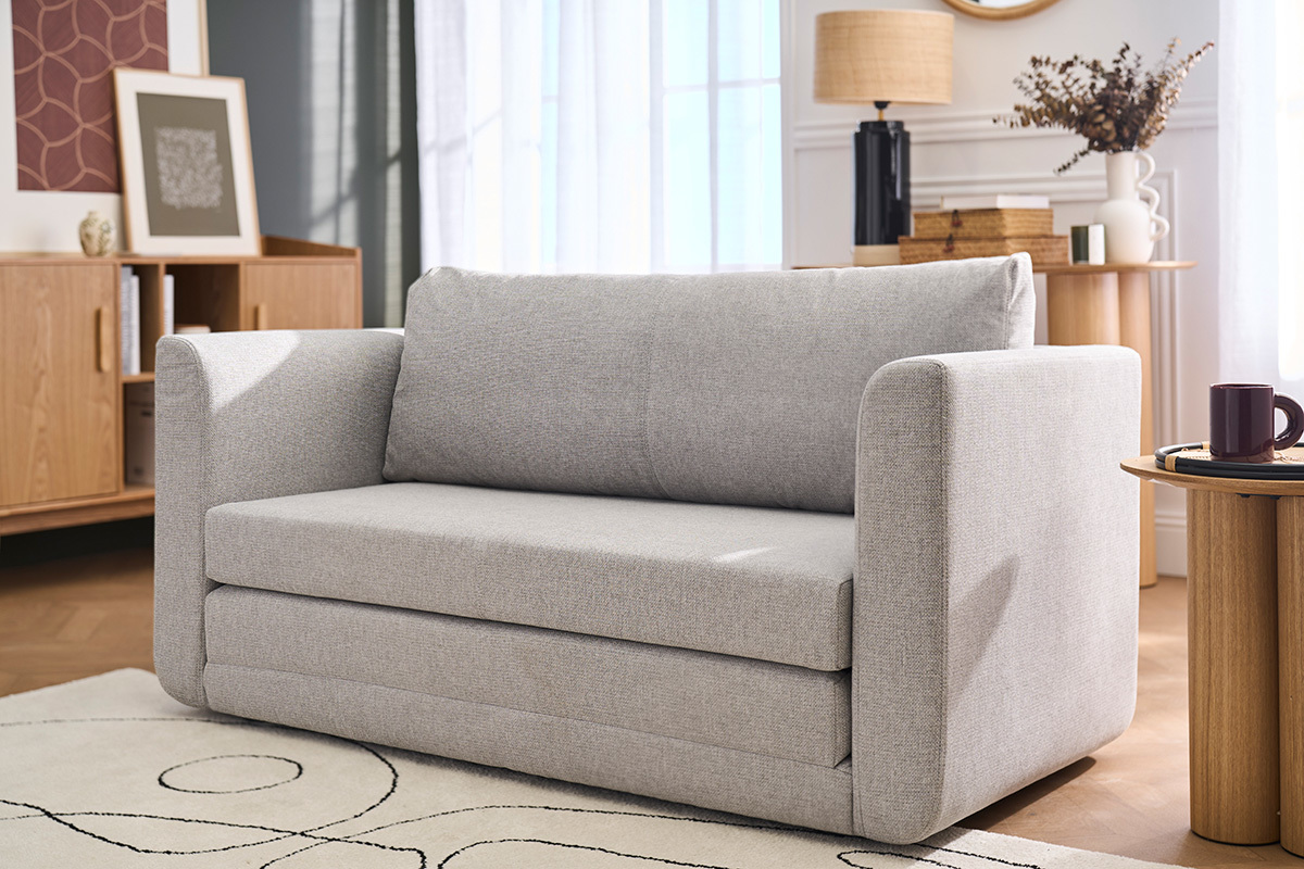 Zweisitzer-Schlafsofa aus hellem grauen Stoff, Frontansicht, in einem modernen Wohnzimmer.